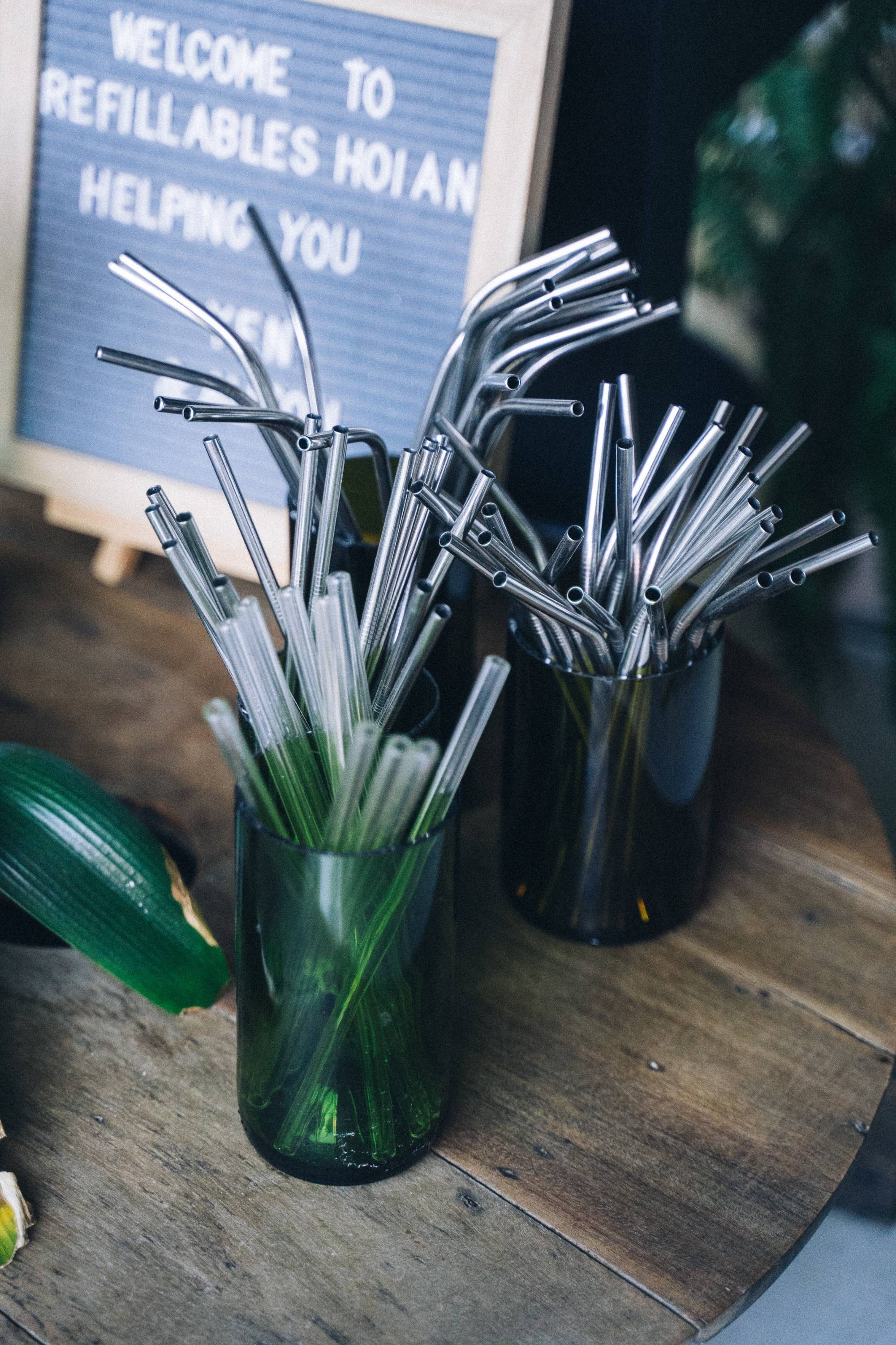 Metal straws in a cup and a sign in the background on top a wooden table